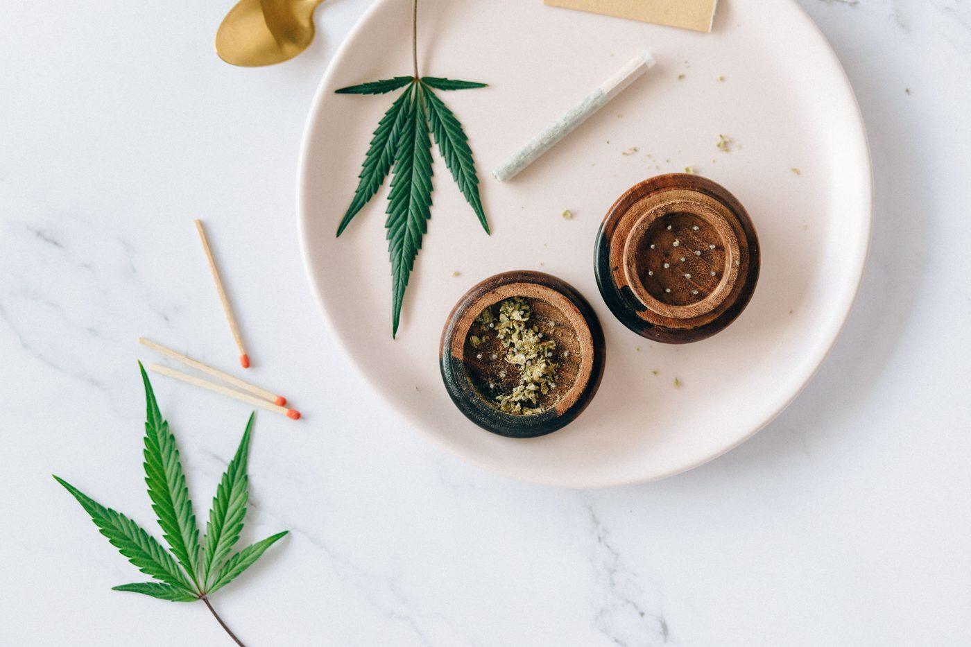 Cannabis flower in a grinder beside a pre-roll