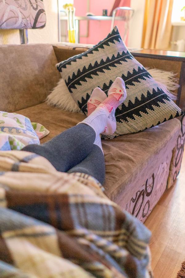 Person resting on a sofa with feet up under a plaid blanket