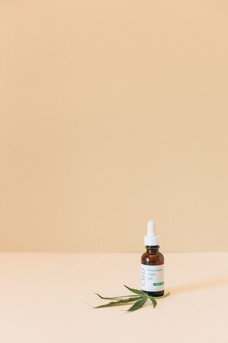 CBD dropper bottle beside a cannabis leaf